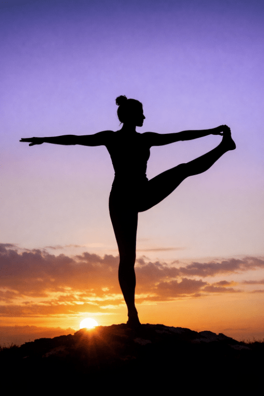Yoga Pose Silhouette of a person balancing in a yoga pose on one leg at sunrise, with the sun low on the horizon and a gradient sky shifting from orange to purple.